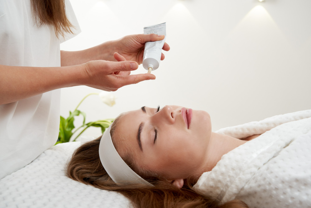 cosmetologist applying cream female face woman having facial treatment spa salon