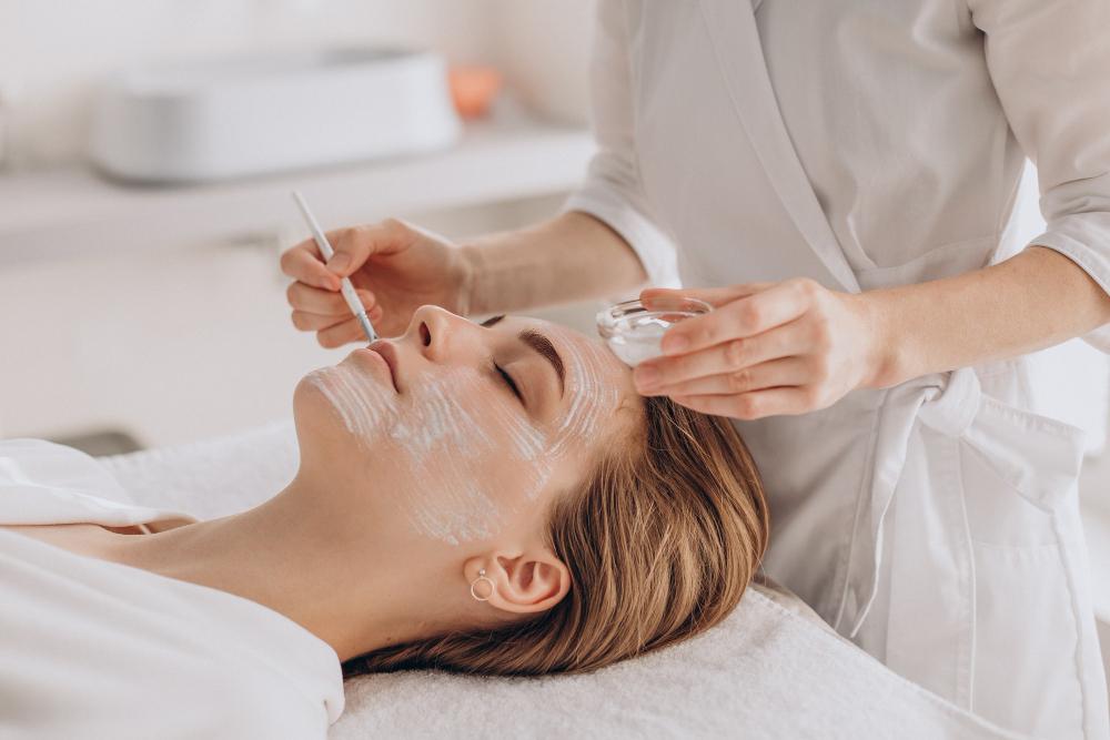 cosmetologist doing face treatment applying face mask